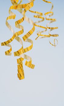 Arrangement of Five Striped Yellow Curly Streamers Hanging Down isolated on Blue background