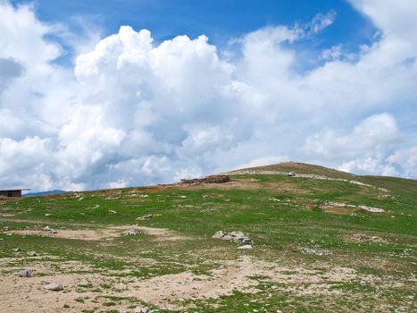 Green grass hill and cloudy blue sky