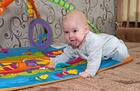 Portrait of the smiling baby crawling on a bed.