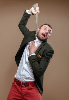A young man in a green jacket hung on his tie. Beige background.