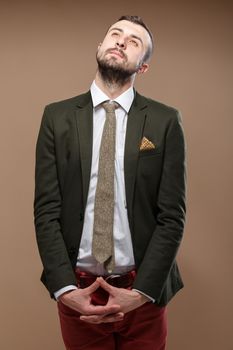 Dreaming Young stylish man in a green suit and orange jeans. Beige background