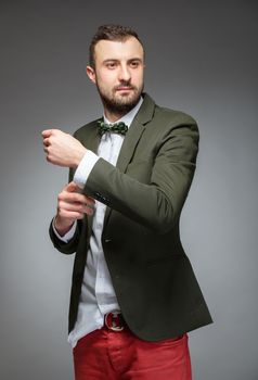 Portrait of handsome stylish man in elegant green suit. Grey background.