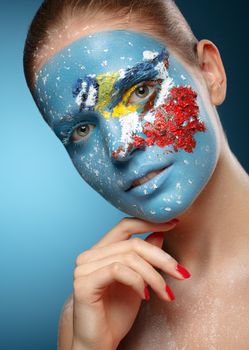 Beautiful fashion model with face art in winter style. Textural makeup. Tit on a branch of rowan.