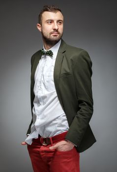 Portrait of handsome stylish man in elegant green suit. Grey background.