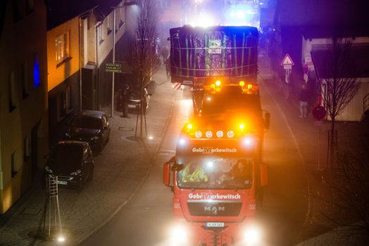 OSTFILDERN-SCHARNHAUSEN, GERMANY - DECEMBER 12, 2013: A heavy tunnel digging machinery is loaded on a flatbed trailer and carried to the construction site of Stuttgart 21 at night on December 12, 2013 in Ostfildern-Scharnhausen near Stuttgart, Germany. S21 is one of the most expensive and controversial railway projects ever with regular demonstrations against the plans to move the existing station underground going on.