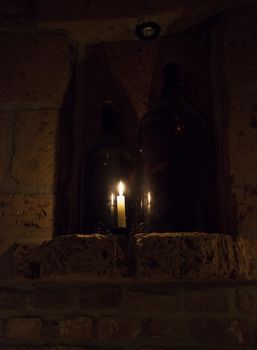 Decorative candle near two big bottles in the darkness