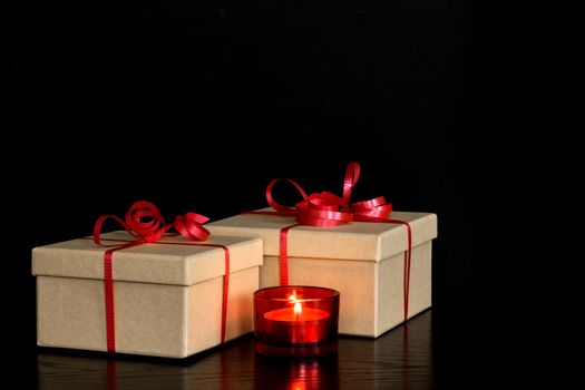 Simple elegant presents and red candlelight on dark background.
