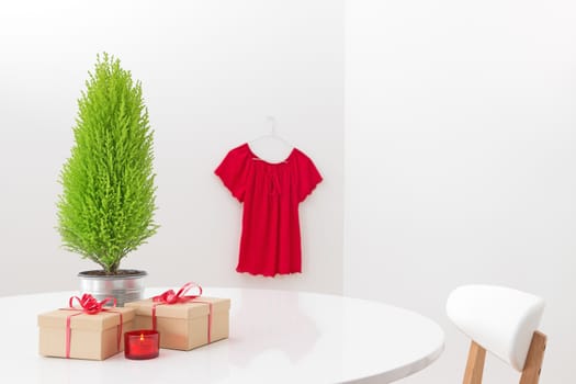 Little Christmas tree and gifts on the table, and red blouse hanging on the wall.