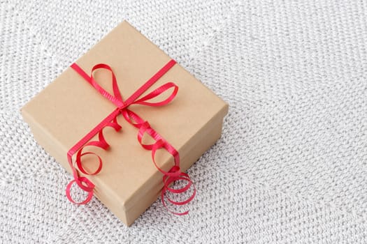 Simple present with red ribbon on a knitted background.