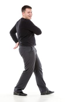 Smiling confident overweight man walking along swinging his arms or dancing and looking at the camera with a friendly smile of pleasure