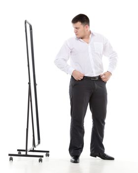 Overweight man admiring himself in a standing mirror as he checks the fit of his clothing and his appearance while dressing in the morning