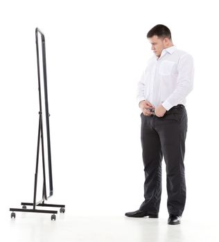 Overweight man admiring himself in a standing mirror as he checks the fit of his clothing and his appearance while dressing in the morning