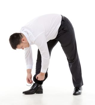 Supple businessman bending down to do up his shoelaces on his stylish leather shoes while dressing in the morning or because they have come loose during the day