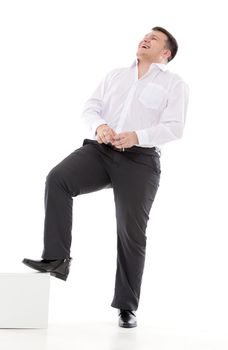 Stylish man in a leaning on a low pedestal laughs, isolated on white