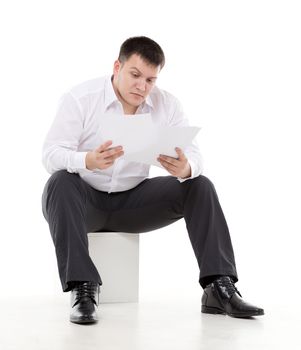 Businessman reading a report with scepticism raising his eyebrow in disbelief at the information