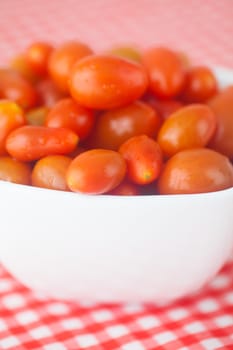 cherry tomatos in bowl on checkered fabric