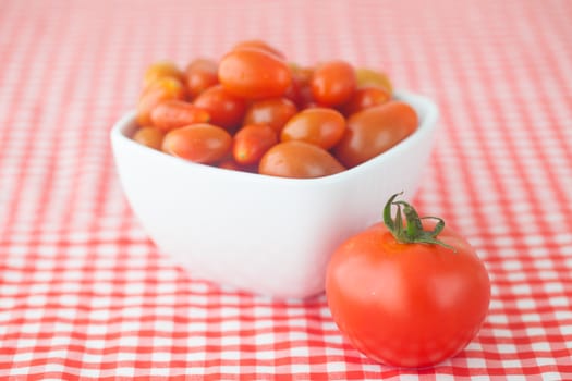 cherry tomatos and tomatos in bowl on checkered fabric
