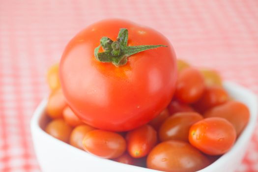 cherry tomatos and tomatos in bowl on checkered fabric