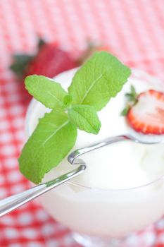 ice cream with mint in a glass bowl and strawberry on plaid fabric