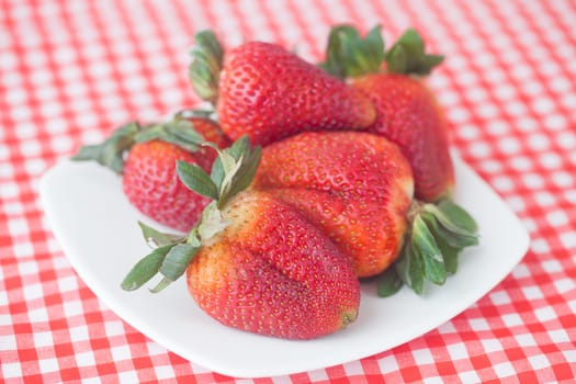 strawberries in bowl on checkered fabric