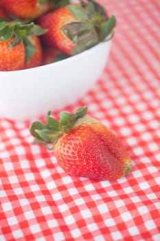 strawberries in bowl on checkered fabric