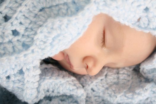Sleeping baby boy wrapped in a wool blanket