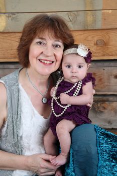 Grandmother and baby granddaughter against wooden background