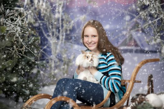 Girl on a sled in the winter forest with rabbit