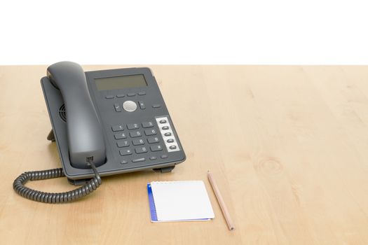 phone on desk with notepad in white background. Wooden desk.