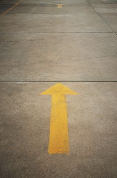 A yellow arrow on old concrete road