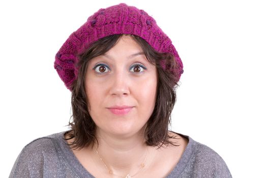 Attractive woman wearing a purple knitted winter cap opening her eyes wide in astonishment and scepticism to show her disbelief, isolated on white