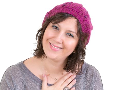 Woman wearing a knitted purple beanie showing her heartfelt gratitude holding her hand to her chest with a lovely sincere smile isolated on white