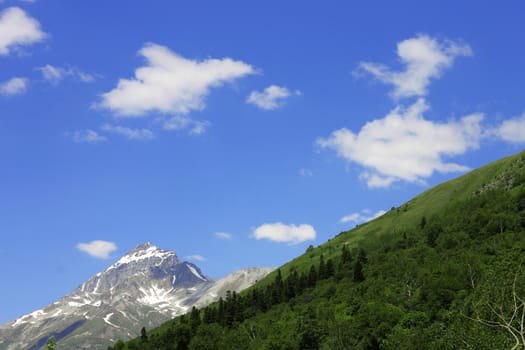 Snowy caucasus mountains and green forest under