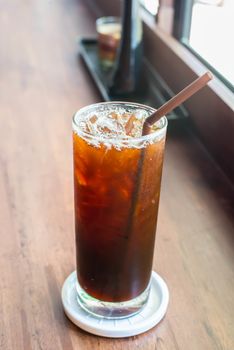 Iced black coffee on the wooden table in coffee cafe.