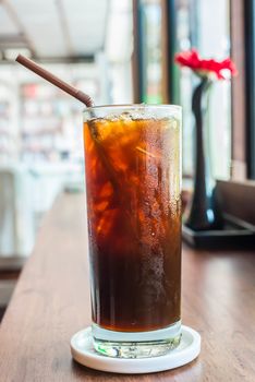Iced black coffee on the wooden table in coffee cafe.