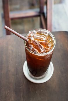 Iced black coffee on the wooden table in coffee cafe.