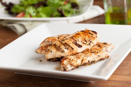 Freshly prepared grilled chicken breasts and salad ingredients.