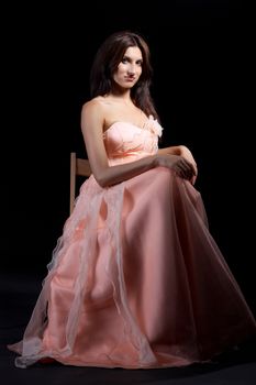 Young women dressed in a pink dress at dark background