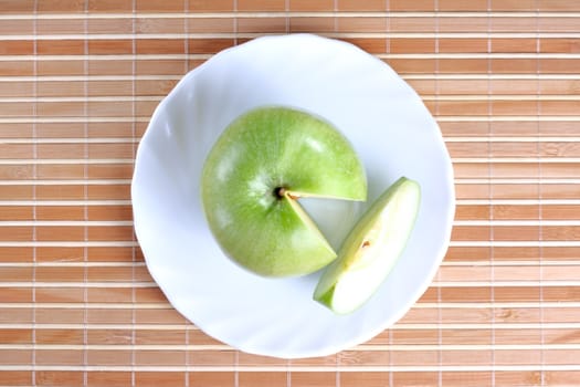 Apple with a piece on the plate at the textured background