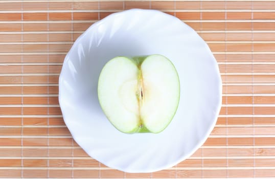 Half of apple on the plate at textured background