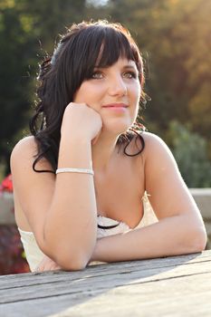 Girl in the wedding dress sitting on the bench neat the table