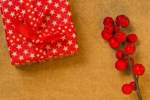 Red present box with white stars and berries on golden background