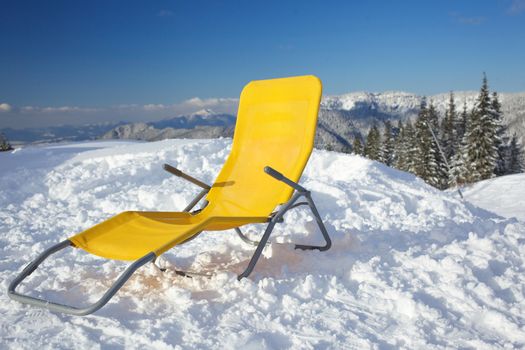 Concept of relax. Chair on top of mountain range at winter season sunny day with blue sky in background.