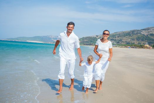 Photo of happy family running on the beach