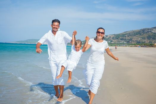 Photo of happy family running on the beach