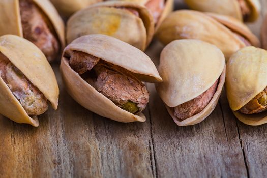 The pistachios heap against the background of wooden boards