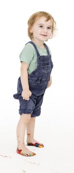child with painted feet holding trousers up. studio shot in grey background