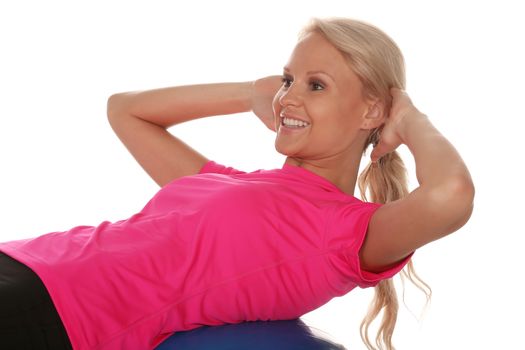 Beautiful young blond lady athlete doing sit ups on an exercise ball