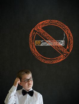 Scratching head thinking boy dressed up as business man with no smoking chalk sign on blackboard background