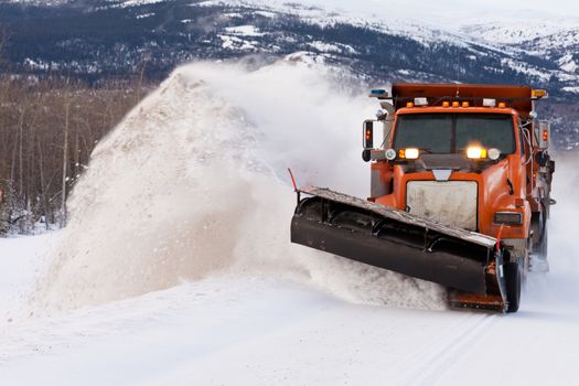 Snow plough truck clearing road after whiteout winter snowstorm blizzard for vehicle access